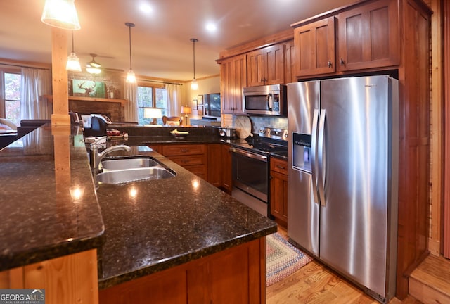 kitchen featuring sink, dark stone countertops, pendant lighting, stainless steel appliances, and backsplash