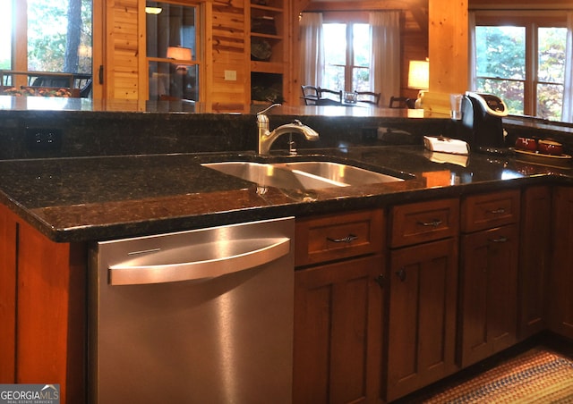 kitchen featuring stainless steel dishwasher, sink, and dark stone countertops