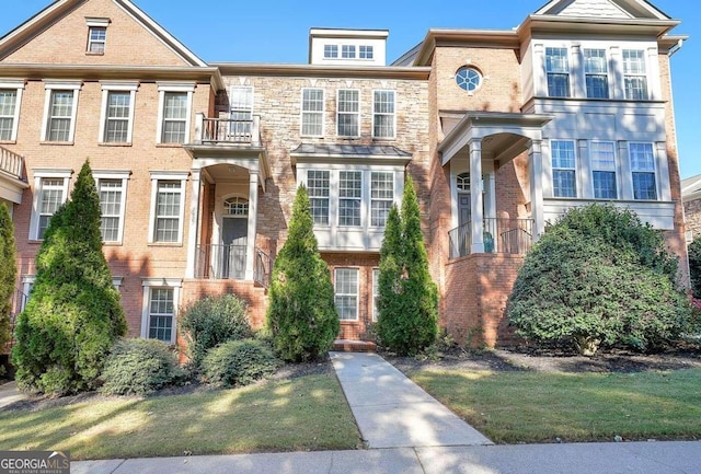 townhome / multi-family property featuring a front yard and a balcony