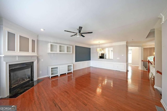 unfurnished living room with crown molding, hardwood / wood-style flooring, a high end fireplace, and ceiling fan