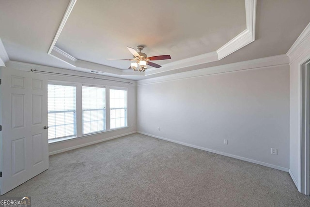 spare room featuring light carpet, crown molding, a tray ceiling, and ceiling fan