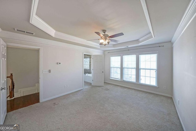 carpeted empty room with crown molding, a tray ceiling, and ceiling fan