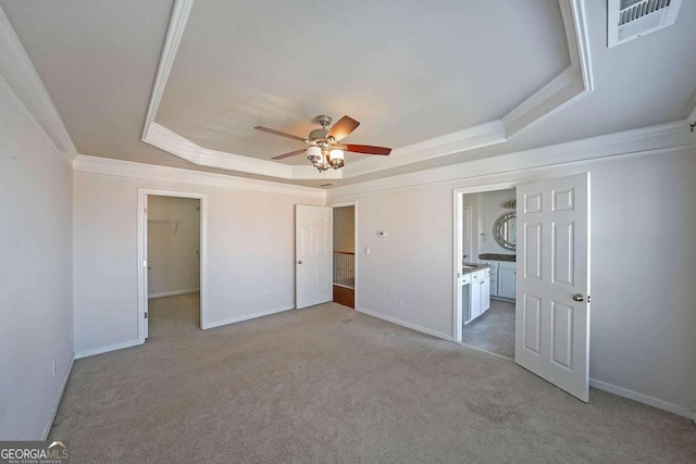 unfurnished bedroom with crown molding, light colored carpet, and a raised ceiling