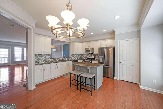 kitchen featuring a breakfast bar, white cabinetry, light hardwood / wood-style flooring, stainless steel appliances, and a center island