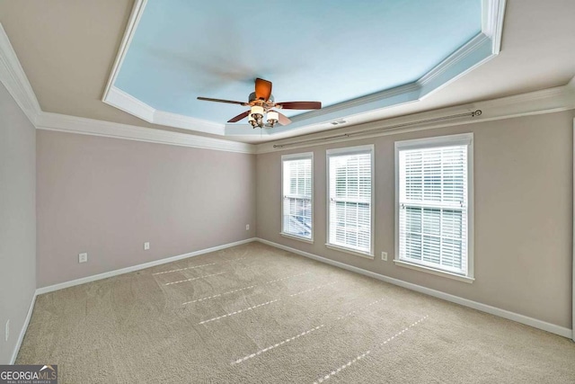 empty room with ceiling fan, a raised ceiling, and ornamental molding