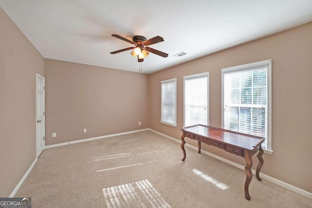 unfurnished office featuring light carpet and ceiling fan