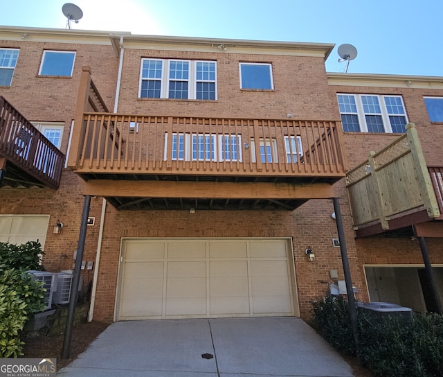 rear view of property featuring central AC unit and a garage