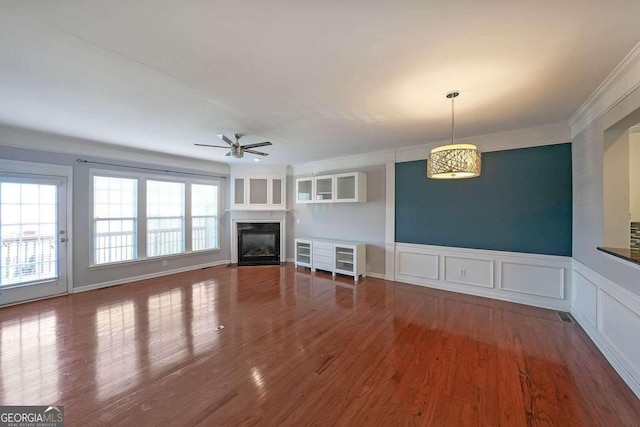 unfurnished living room with ornamental molding, wood-type flooring, and ceiling fan