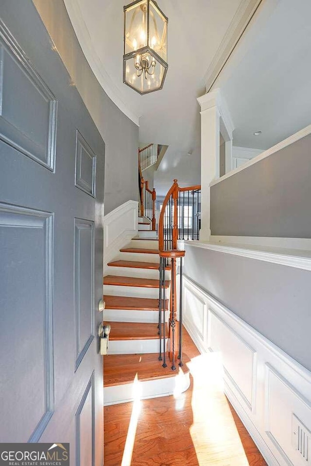 stairs featuring ornamental molding, a chandelier, and hardwood / wood-style floors