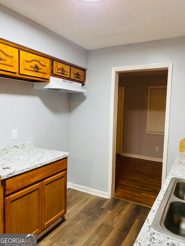 kitchen featuring sink, light stone counters, and dark hardwood / wood-style flooring