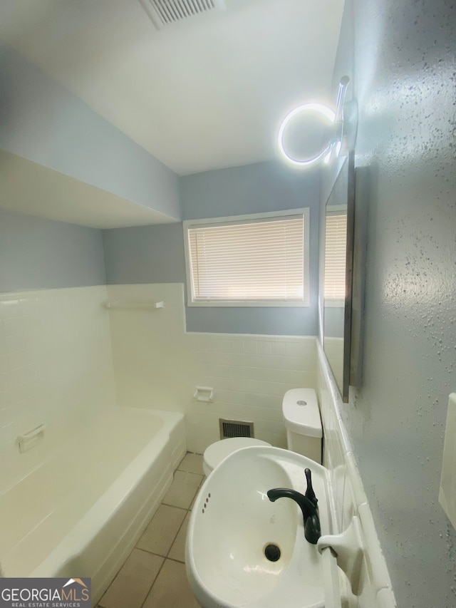 bathroom with tile walls, toilet, a tub to relax in, sink, and tile patterned floors