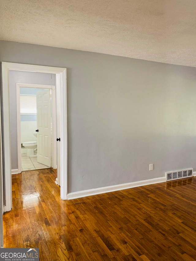 spare room featuring a textured ceiling and wood-type flooring