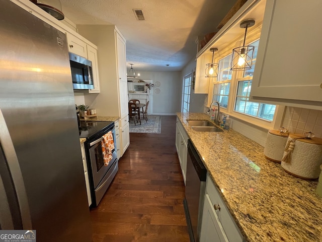 kitchen with white cabinetry, stainless steel appliances, sink, and pendant lighting