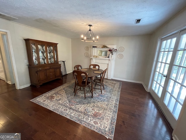 dining space with a notable chandelier, a textured ceiling, and dark hardwood / wood-style flooring