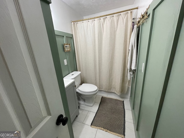 bathroom with toilet, a shower with curtain, vanity, and tile patterned floors