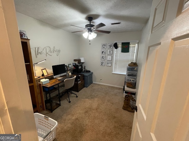 carpeted office space featuring ceiling fan and a textured ceiling