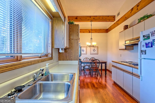 kitchen with pendant lighting, white cabinets, beam ceiling, hardwood / wood-style flooring, and white refrigerator