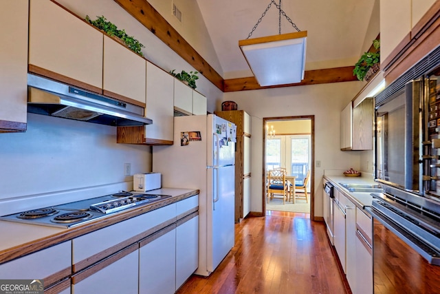 kitchen featuring lofted ceiling, white cabinets, hanging light fixtures, appliances with stainless steel finishes, and light hardwood / wood-style flooring