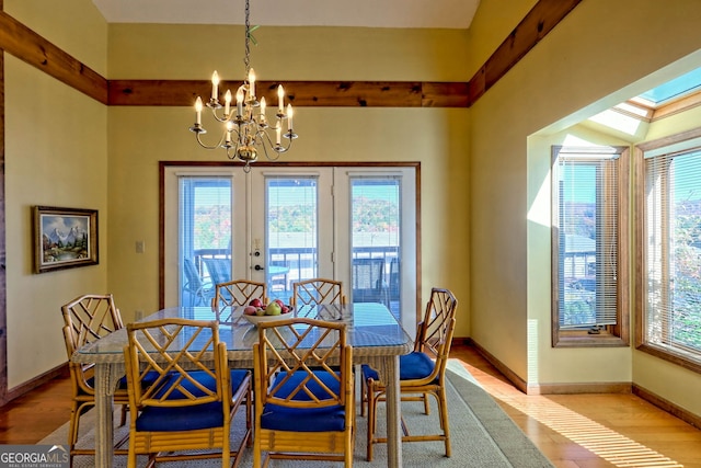 dining space with french doors, light hardwood / wood-style floors, and a chandelier