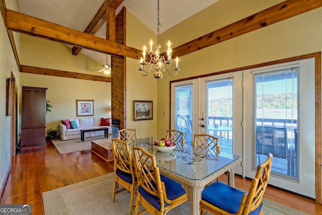 dining room with high vaulted ceiling, beamed ceiling, dark wood-type flooring, ceiling fan with notable chandelier, and french doors