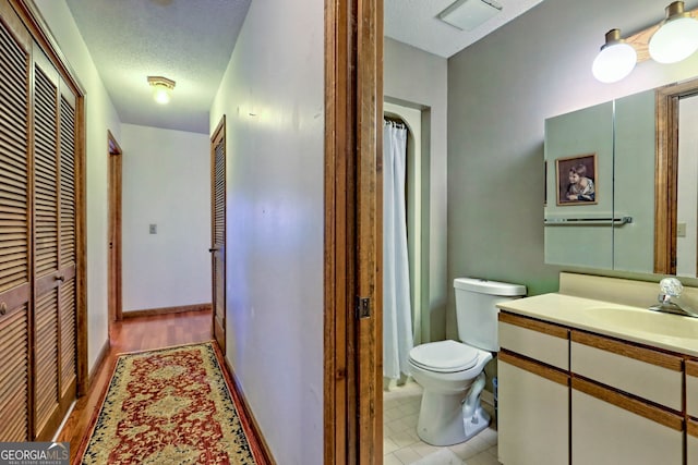 bathroom with tile patterned floors, toilet, curtained shower, vanity, and a textured ceiling