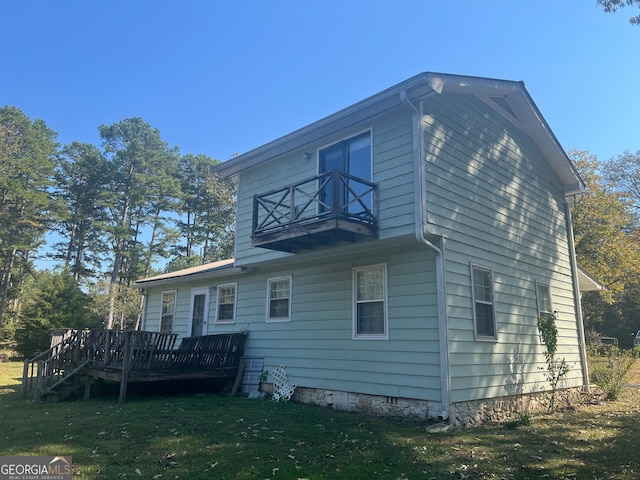 back of house with a yard, a deck, and a balcony