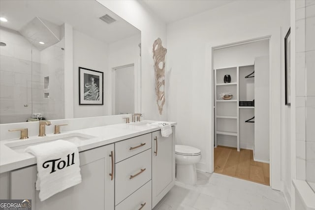 bathroom with vanity, tiled shower, hardwood / wood-style floors, and toilet