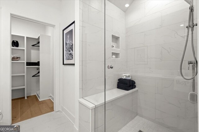 bathroom featuring a shower with door, hardwood / wood-style flooring, and vaulted ceiling