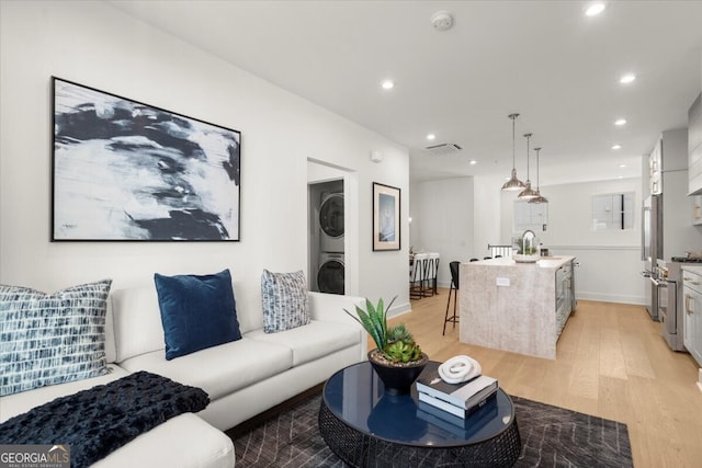 living room with stacked washer / dryer and light hardwood / wood-style flooring