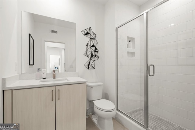 bathroom with toilet, a shower with shower door, vanity, and tile patterned flooring