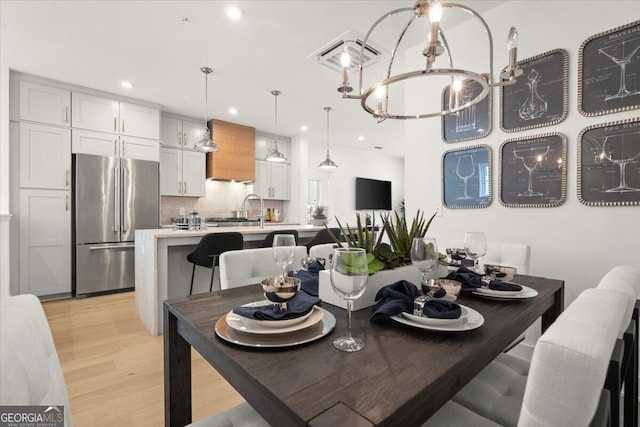 dining room with sink, a notable chandelier, and light hardwood / wood-style floors