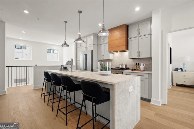 kitchen with an island with sink, stainless steel appliances, and light wood-type flooring