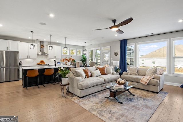 living room with ceiling fan, sink, and light hardwood / wood-style flooring