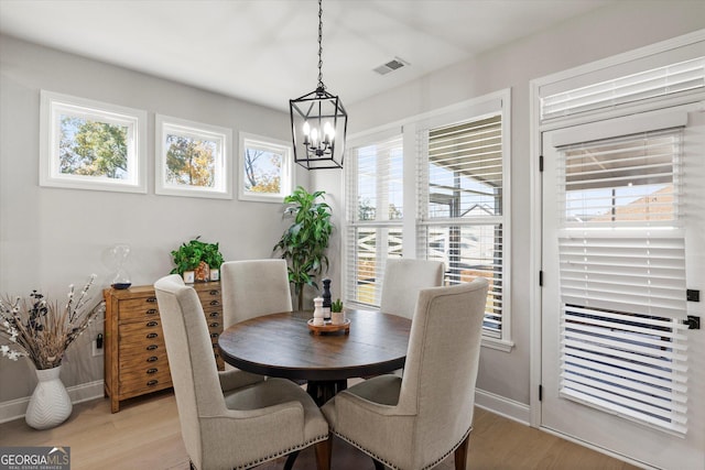 dining room with light wood-type flooring and an inviting chandelier