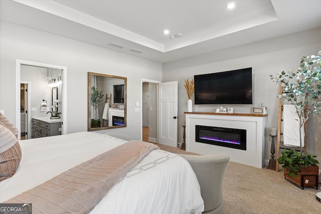 bedroom featuring ensuite bathroom, carpet, sink, and a raised ceiling