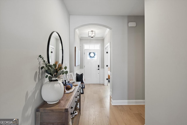 foyer entrance with light hardwood / wood-style floors and crown molding