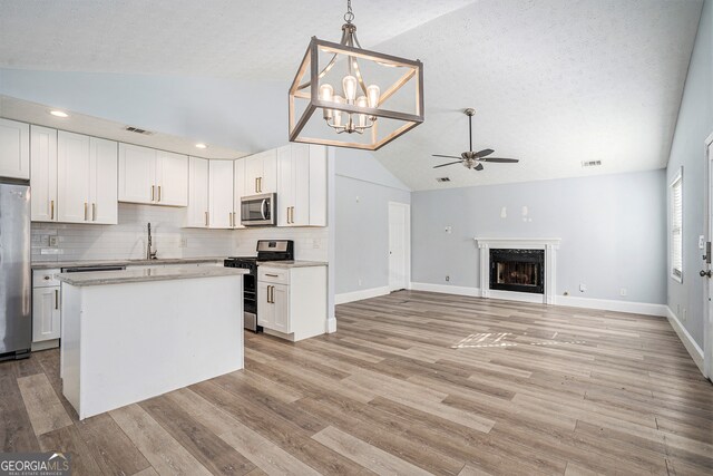 kitchen with appliances with stainless steel finishes, light hardwood / wood-style flooring, decorative light fixtures, and white cabinetry