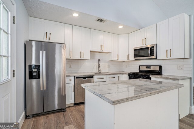 kitchen featuring hardwood / wood-style floors, appliances with stainless steel finishes, and white cabinetry