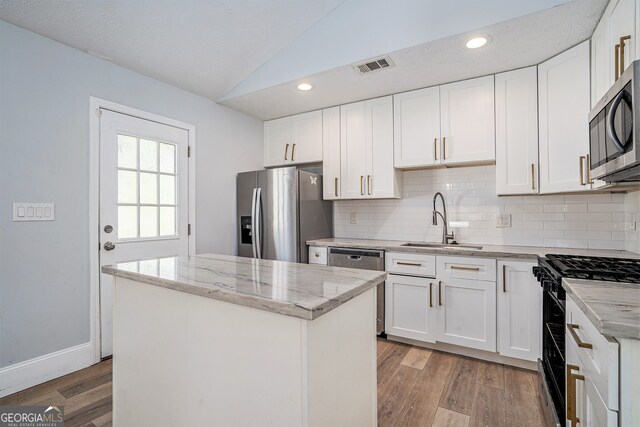 kitchen with white cabinets, a kitchen island, light wood-type flooring, sink, and stainless steel appliances