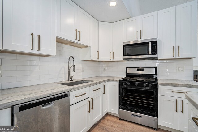 kitchen featuring white cabinetry, stainless steel appliances, sink, and light wood-type flooring