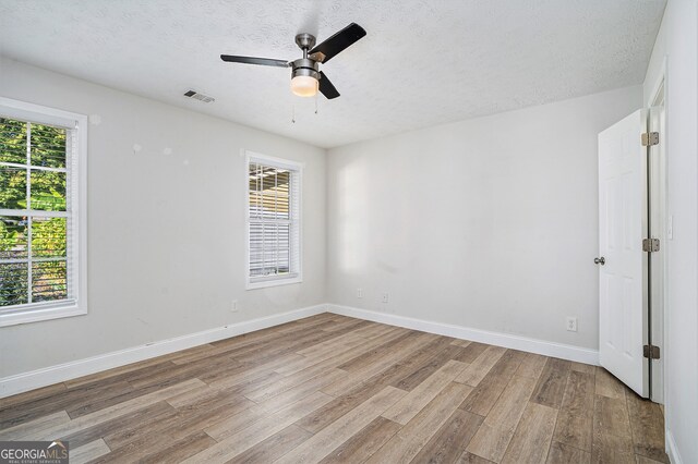 empty room featuring light hardwood / wood-style flooring, a textured ceiling, and ceiling fan