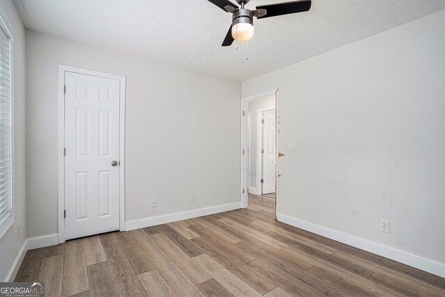 unfurnished bedroom featuring a textured ceiling, light wood-type flooring, and ceiling fan