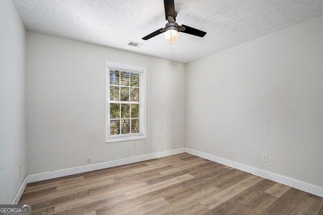 spare room featuring a textured ceiling, light hardwood / wood-style floors, and ceiling fan