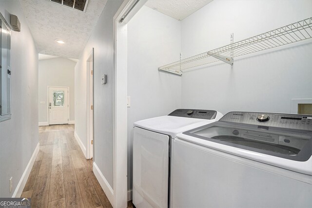 laundry area with a textured ceiling, hardwood / wood-style flooring, and separate washer and dryer