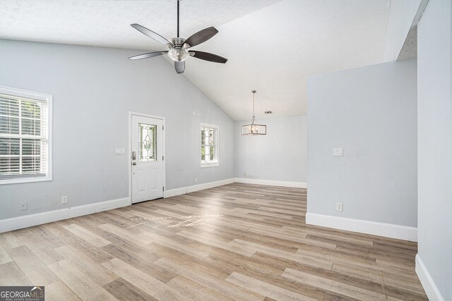 interior space featuring high vaulted ceiling, a textured ceiling, ceiling fan with notable chandelier, and light wood-type flooring