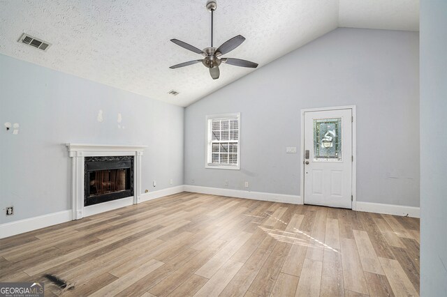 unfurnished living room with light hardwood / wood-style floors, high vaulted ceiling, a textured ceiling, and ceiling fan