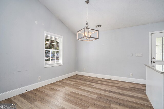 unfurnished dining area with lofted ceiling, a healthy amount of sunlight, and wood-type flooring