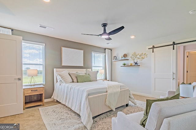 bedroom featuring ceiling fan, light carpet, and a barn door