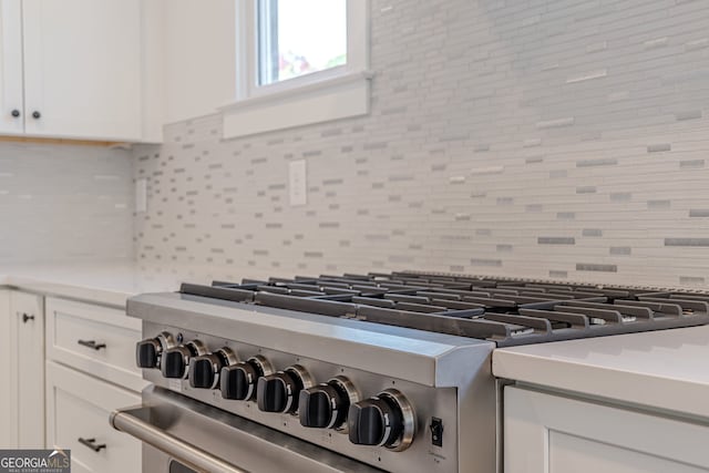 interior details with high end stove, decorative backsplash, and white cabinets