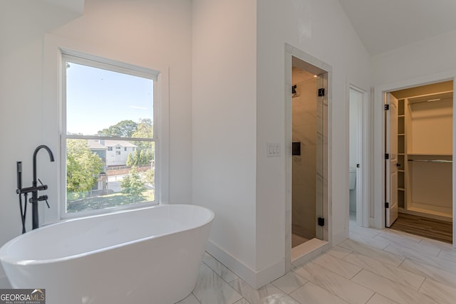 bathroom with a wealth of natural light, vaulted ceiling, and plus walk in shower